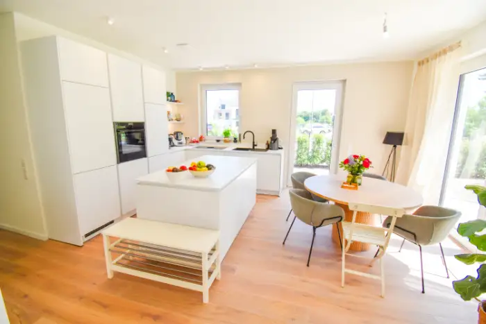 Moderne, offene Küche in Weiß mit Parkettboden und einem Esstisch für vier Personen